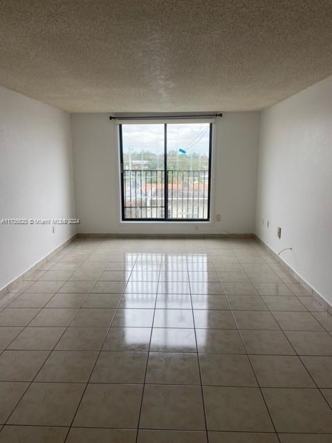 unfurnished room with tile patterned flooring and a textured ceiling