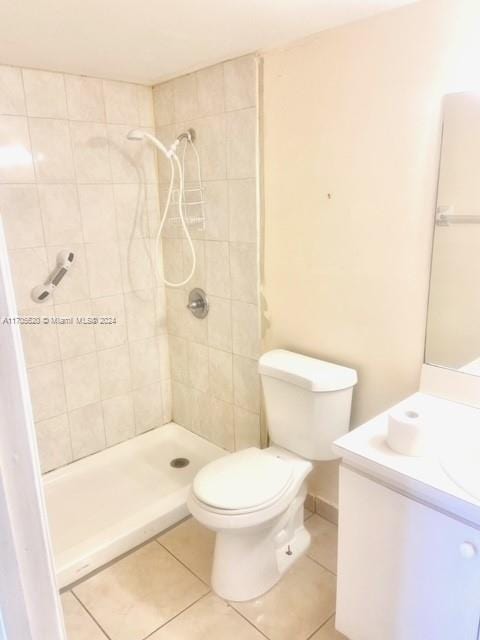 bathroom featuring tile patterned flooring, a tile shower, vanity, and toilet