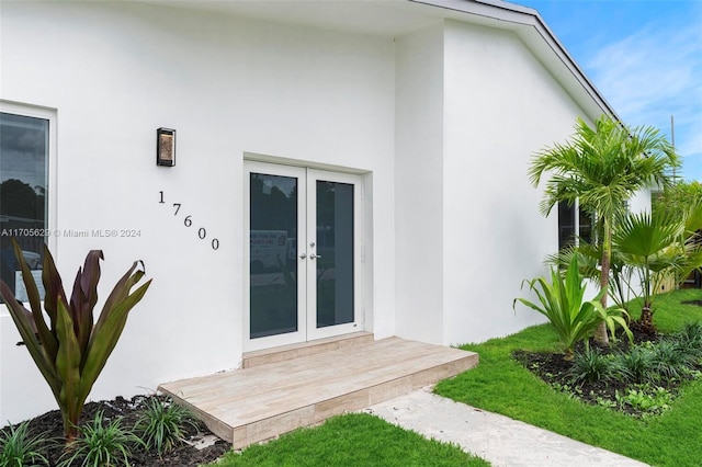 view of exterior entry with a lawn and french doors