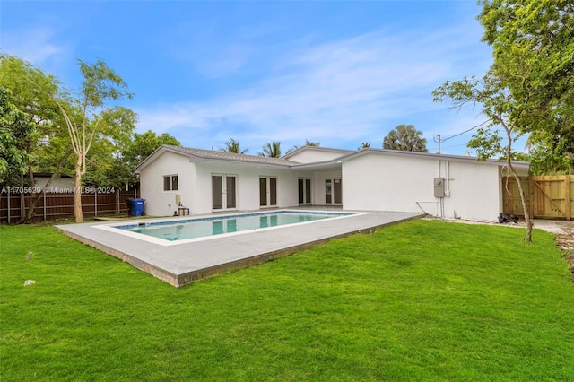 rear view of house with a fenced in pool, a yard, and a patio