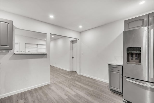 kitchen with gray cabinetry, stainless steel fridge, and light wood-type flooring