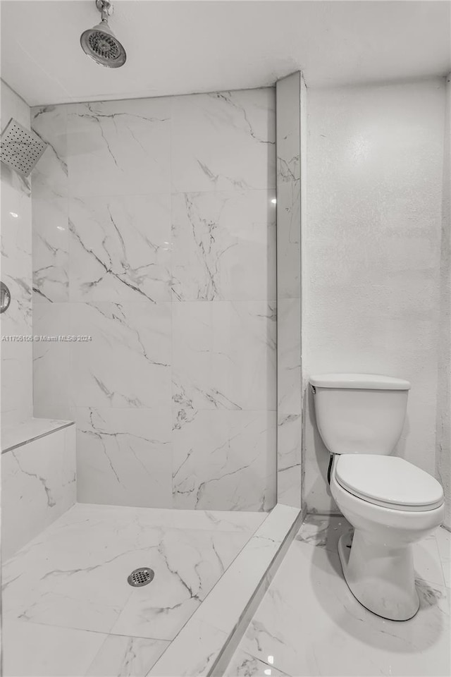 bathroom with a tile shower and toilet