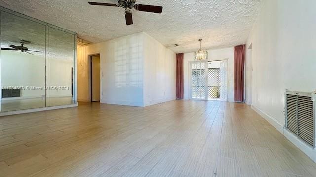 unfurnished room with ceiling fan with notable chandelier, a textured ceiling, and light hardwood / wood-style floors