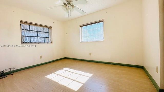 empty room featuring ceiling fan, light wood-type flooring, and a wealth of natural light