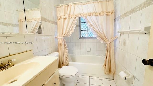 full bathroom with tile patterned floors, vanity, shower / tub combo with curtain, tile walls, and toilet