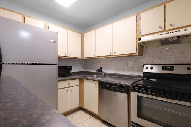 kitchen with appliances with stainless steel finishes, backsplash, light tile patterned floors, and sink