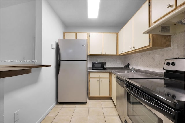 kitchen with sink, decorative backsplash, light tile patterned floors, appliances with stainless steel finishes, and cream cabinetry