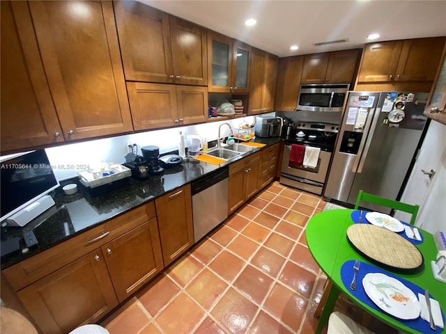 kitchen featuring light tile patterned flooring, stainless steel appliances, dark stone counters, and sink