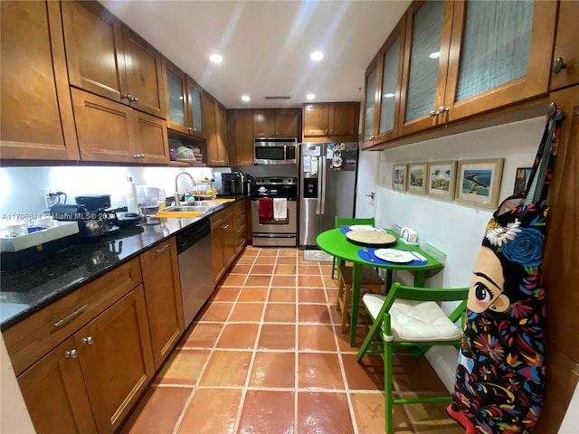 kitchen with sink, light tile patterned floors, dark stone counters, and appliances with stainless steel finishes