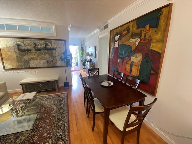 dining space featuring a textured ceiling, hardwood / wood-style flooring, and crown molding