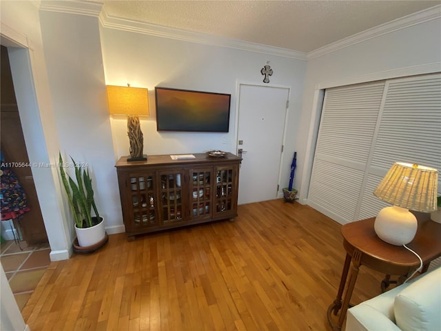 living area with crown molding, a textured ceiling, and hardwood / wood-style flooring