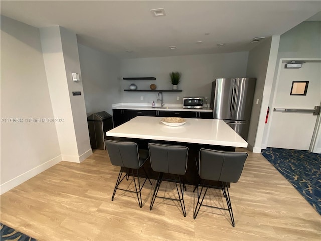 kitchen with a center island, stainless steel refrigerator, and light hardwood / wood-style flooring