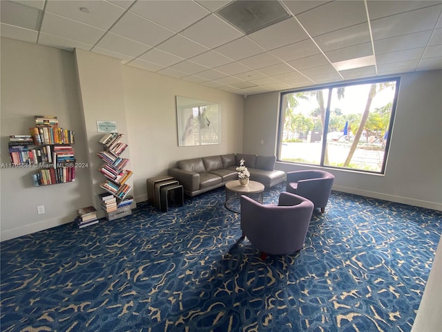 carpeted living room featuring a drop ceiling