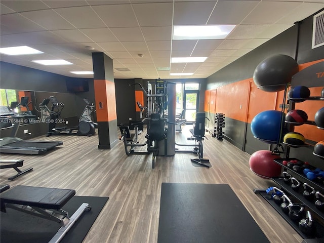 exercise room featuring a paneled ceiling and wood-type flooring