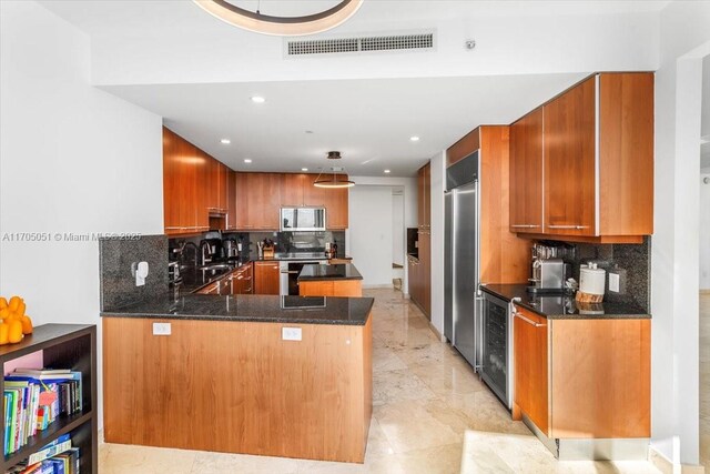 kitchen featuring sink, stainless steel appliances, tasteful backsplash, kitchen peninsula, and dark stone countertops