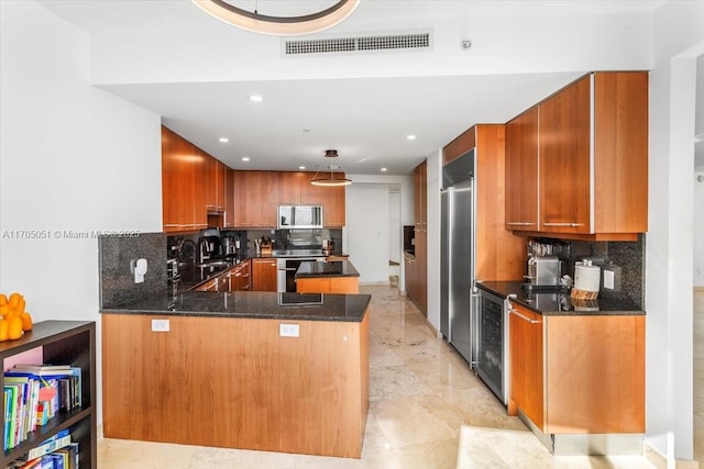 kitchen featuring stainless steel appliances, a peninsula, a sink, visible vents, and brown cabinets