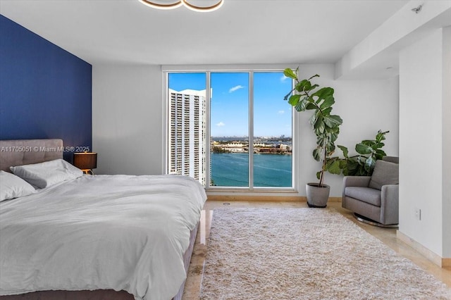 bedroom featuring a wall of windows and a water view