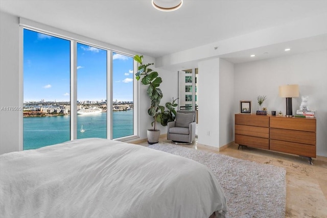 bedroom with expansive windows, a water view, and recessed lighting