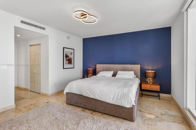 bedroom with baseboards, an accent wall, and visible vents