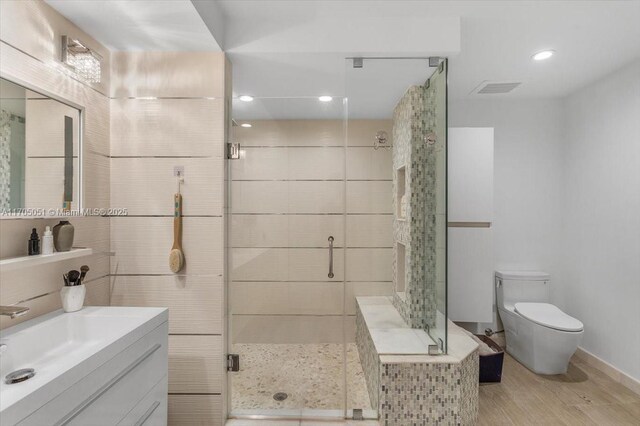 bathroom with hardwood / wood-style floors, vanity, toilet, and an enclosed shower