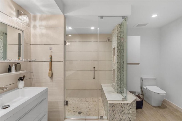 full bathroom featuring a stall shower, visible vents, toilet, wood finished floors, and vanity