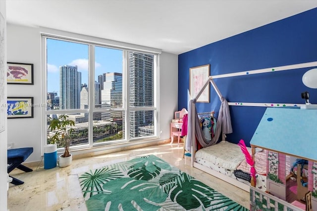 bedroom featuring marble finish floor, multiple windows, and a city view