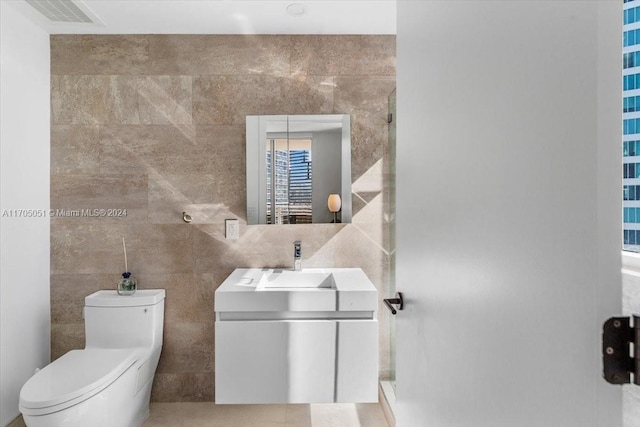 bathroom with vanity, tile walls, and toilet