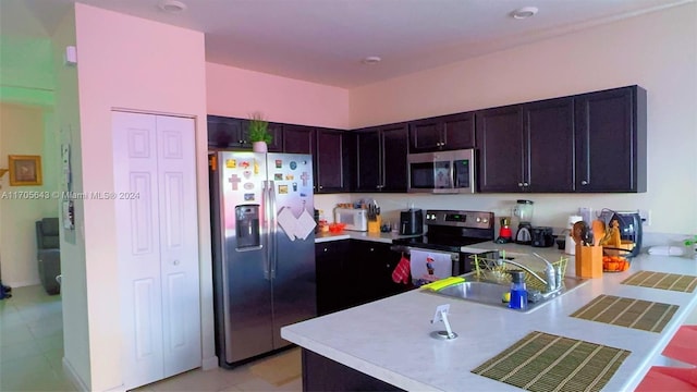 kitchen with sink, kitchen peninsula, dark brown cabinets, light tile patterned floors, and appliances with stainless steel finishes