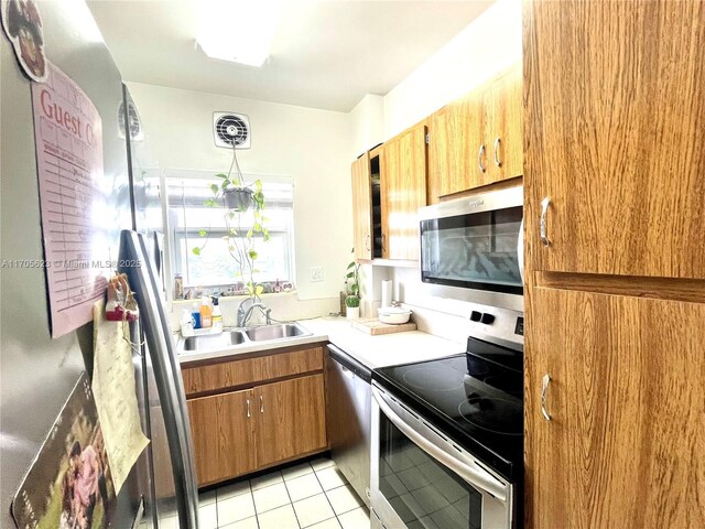 4747 Collins Ave Unit 503, Miami Beach, FL 33140 - kitchen with stainless steel appliances, a sink, light tile patterned flooring, brown cabinetry, and light countertops
