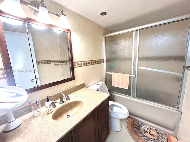 full bathroom featuring shower / bath combination with glass door, tile patterned floors, vanity, and tile walls