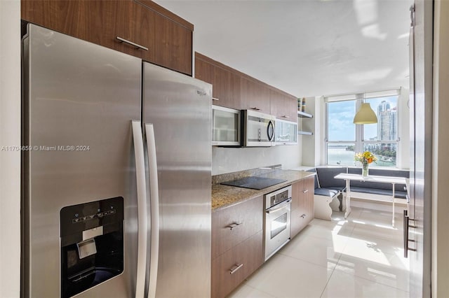 kitchen with light tile patterned floors, stainless steel appliances, and light stone counters