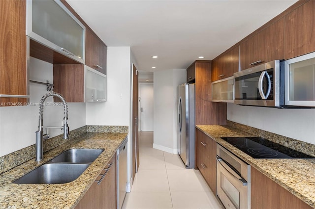 kitchen featuring light tile patterned flooring, light stone countertops, sink, and appliances with stainless steel finishes