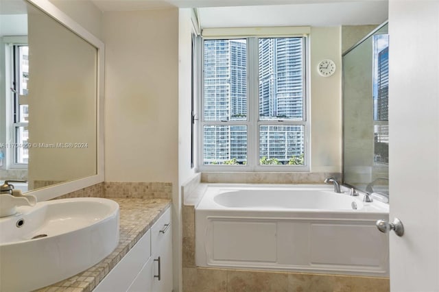 bathroom featuring vanity, tiled bath, and plenty of natural light