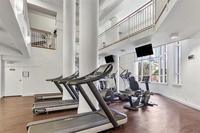 gym with a towering ceiling and dark wood-type flooring