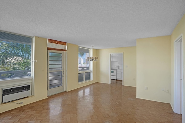 spare room with a notable chandelier, parquet floors, a textured ceiling, and heating unit