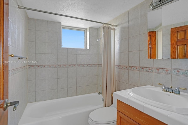 full bathroom with vanity, toilet, a textured ceiling, tile walls, and shower / tub combo with curtain