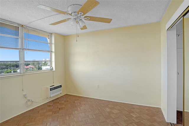 empty room featuring ceiling fan, an AC wall unit, a textured ceiling, and light parquet flooring