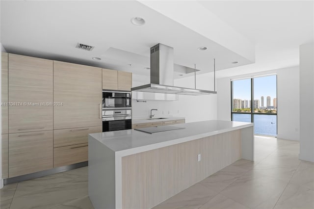 kitchen featuring island exhaust hood, sink, black appliances, light brown cabinets, and a large island