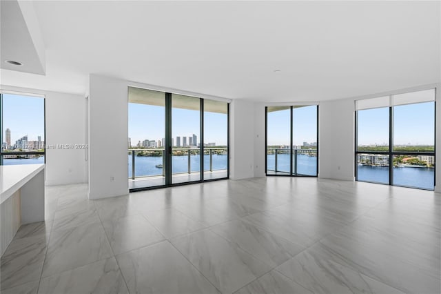 unfurnished room with expansive windows and a water view