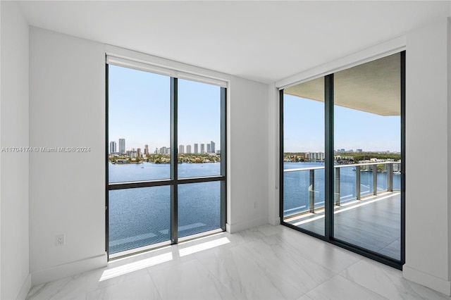 spare room with a water view and floor to ceiling windows