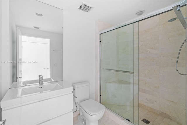 bathroom featuring tile patterned floors, vanity, toilet, and a shower with door