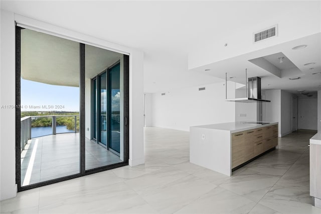 kitchen featuring a water view, floor to ceiling windows, black electric stovetop, and wall chimney exhaust hood