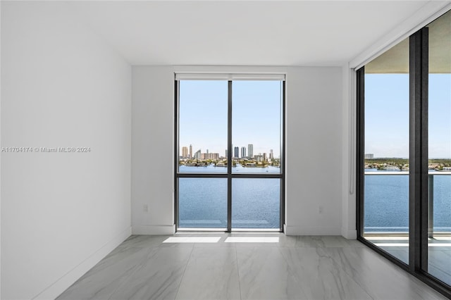 spare room with a water view and floor to ceiling windows