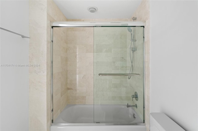 bathroom with toilet and combined bath / shower with glass door