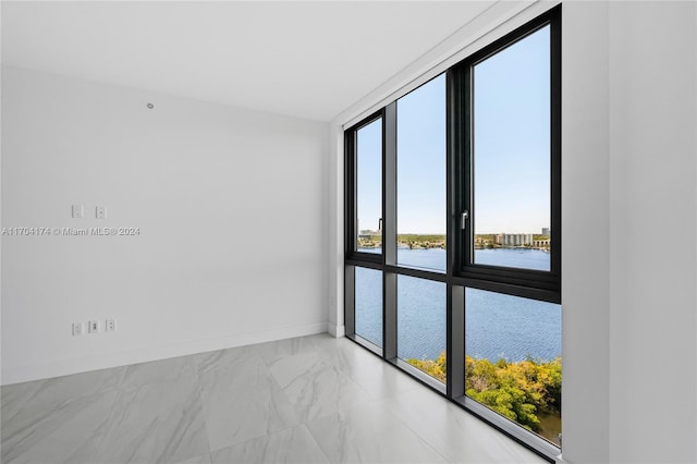 spare room featuring expansive windows and a water view