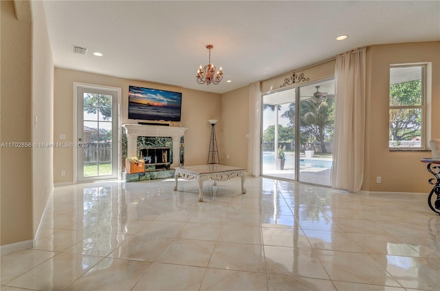 unfurnished living room featuring a chandelier, a wealth of natural light, visible vents, and a fireplace