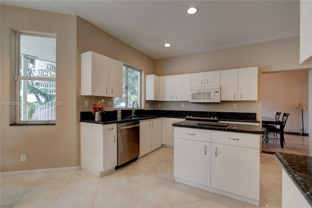 kitchen featuring white microwave, baseboards, white cabinets, and dishwasher