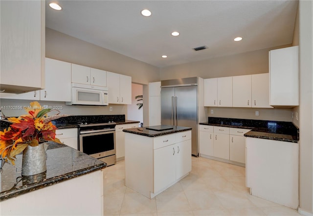 kitchen with appliances with stainless steel finishes, a kitchen island, visible vents, and white cabinets