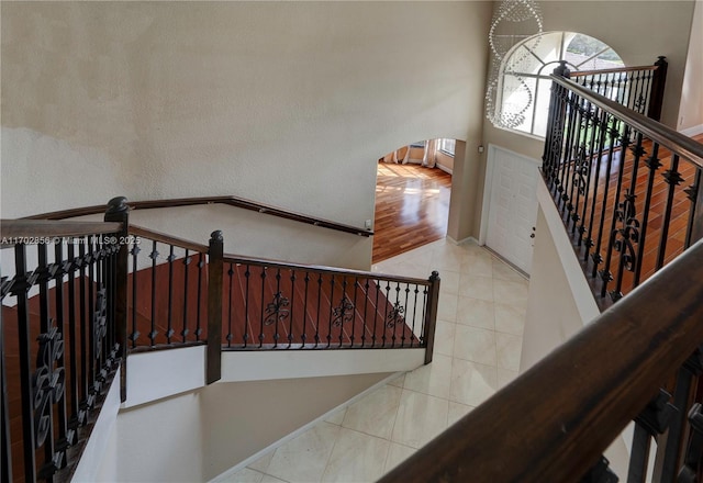 stairs with tile patterned flooring, a high ceiling, arched walkways, and baseboards