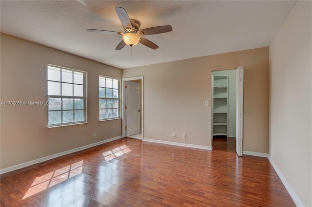 unfurnished room featuring a textured ceiling, ceiling fan, wood finished floors, and baseboards